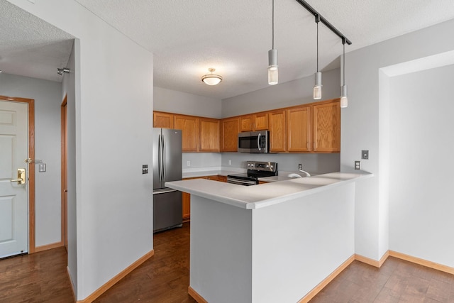 kitchen with dark hardwood / wood-style floors, pendant lighting, kitchen peninsula, stainless steel appliances, and a textured ceiling