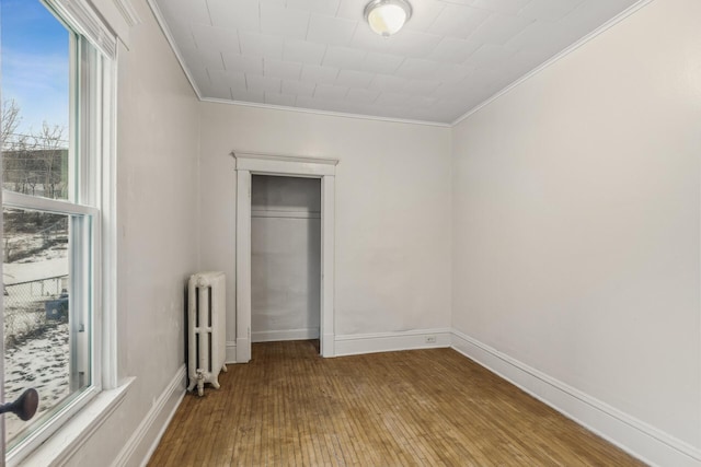 unfurnished bedroom featuring ornamental molding, radiator, a closet, and light wood-type flooring