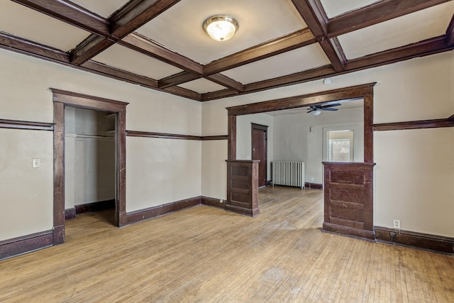 spare room with coffered ceiling, radiator heating unit, ceiling fan, beam ceiling, and light hardwood / wood-style floors