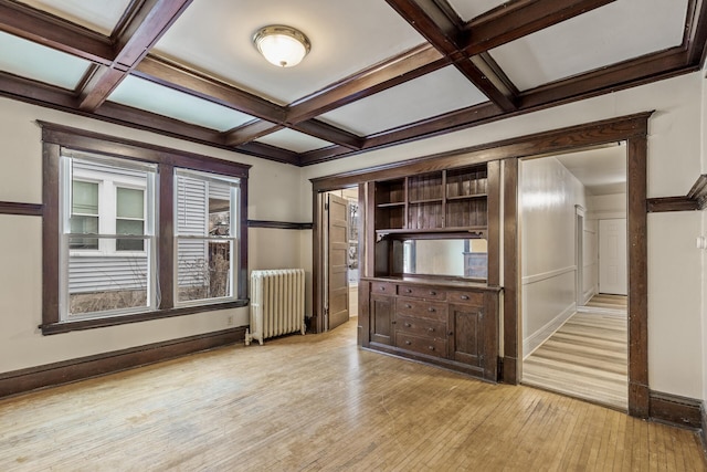 unfurnished living room with coffered ceiling, radiator heating unit, beamed ceiling, and light wood-type flooring