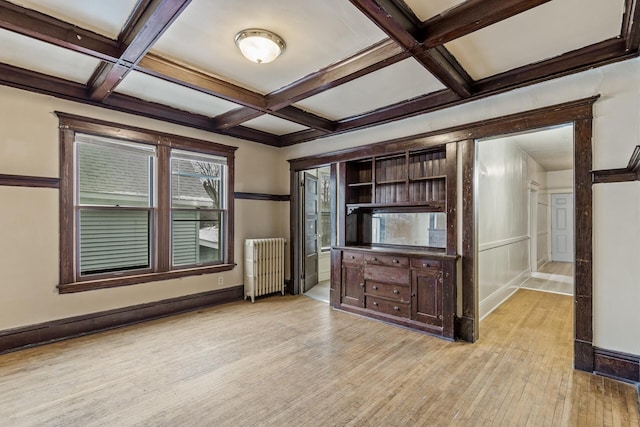 unfurnished living room with radiator heating unit, coffered ceiling, beam ceiling, and light hardwood / wood-style flooring