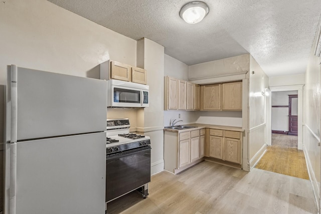 kitchen featuring light brown cabinetry, sink, a textured ceiling, light wood-type flooring, and white appliances