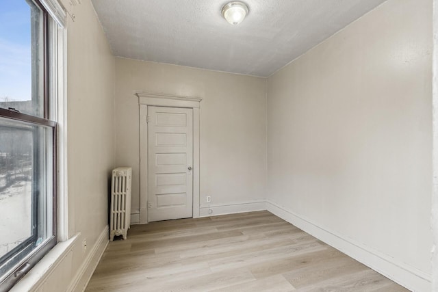 empty room with radiator heating unit, light hardwood / wood-style flooring, and a textured ceiling