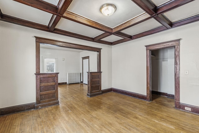 interior space with radiator heating unit, coffered ceiling, beam ceiling, and wood-type flooring