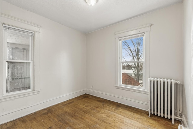 spare room with hardwood / wood-style flooring, radiator, and a textured ceiling