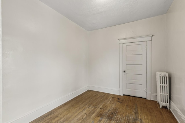 empty room featuring dark hardwood / wood-style flooring and radiator