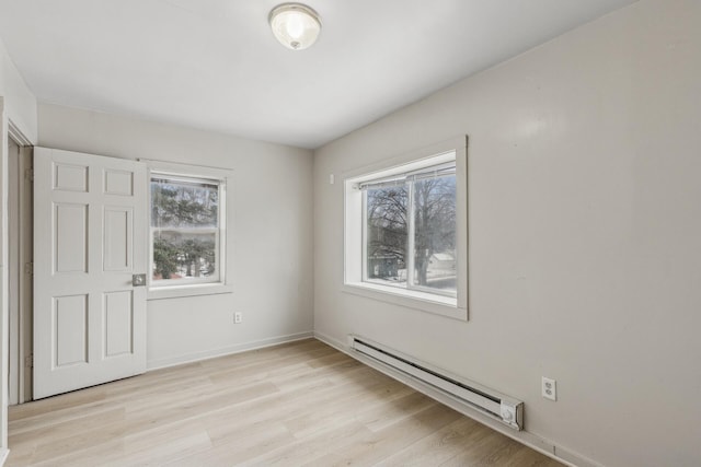 empty room with a baseboard radiator, a healthy amount of sunlight, and light hardwood / wood-style flooring