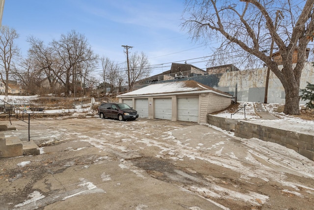 view of snowy exterior featuring a garage and an outdoor structure