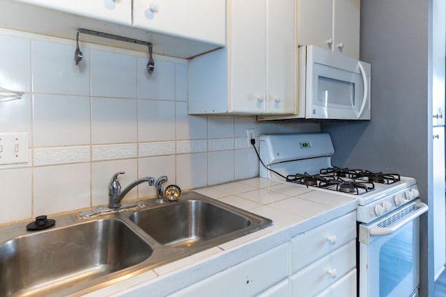 kitchen featuring sink, white appliances, white cabinetry, tasteful backsplash, and tile countertops