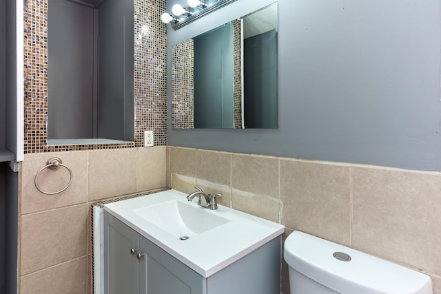 bathroom with vanity, tile walls, and toilet