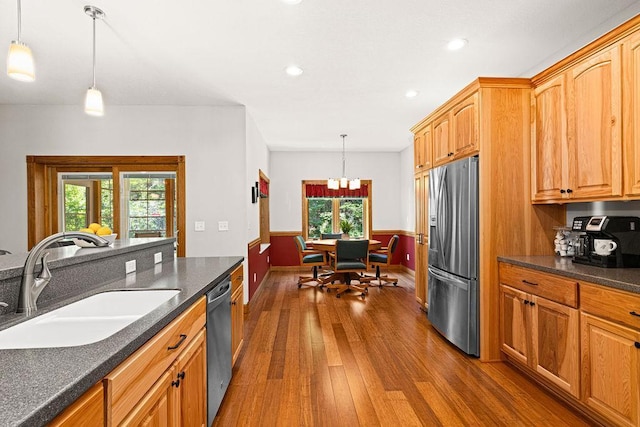 kitchen with stainless steel appliances, dark hardwood / wood-style floors, sink, and hanging light fixtures