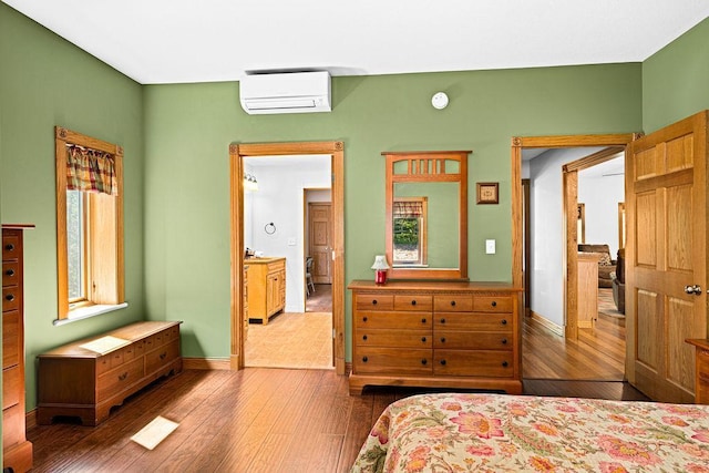 bedroom featuring multiple windows, hardwood / wood-style floors, and a wall unit AC