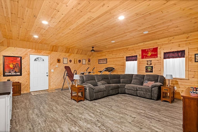 carpeted living room with ceiling fan, wood walls, and wooden ceiling