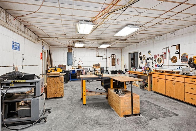 miscellaneous room with concrete flooring, a workshop area, and electric panel