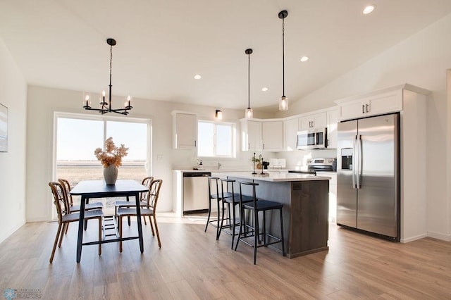 kitchen with white cabinetry, stainless steel appliances, a center island, and hanging light fixtures