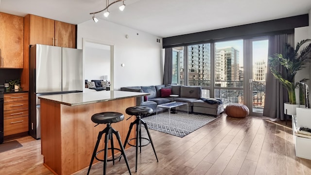 kitchen with a city view, brown cabinetry, freestanding refrigerator, open floor plan, and a kitchen breakfast bar