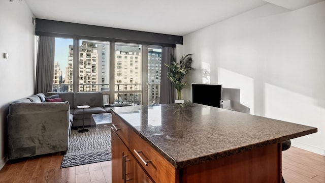 interior space featuring light wood-type flooring, open floor plan, a kitchen island, and dark stone countertops