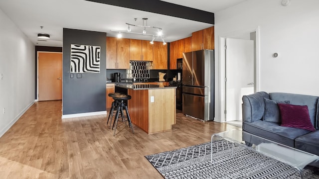 kitchen with dark countertops, a kitchen island, open floor plan, a breakfast bar, and freestanding refrigerator