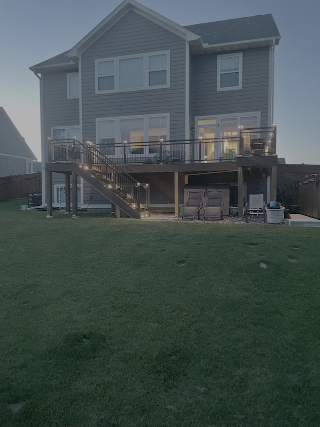 rear view of house featuring a wooden deck and a lawn