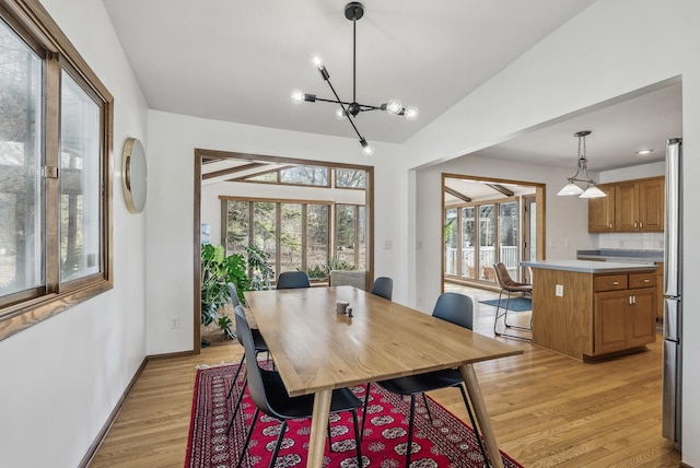 dining space featuring a notable chandelier, vaulted ceiling, and light hardwood / wood-style floors