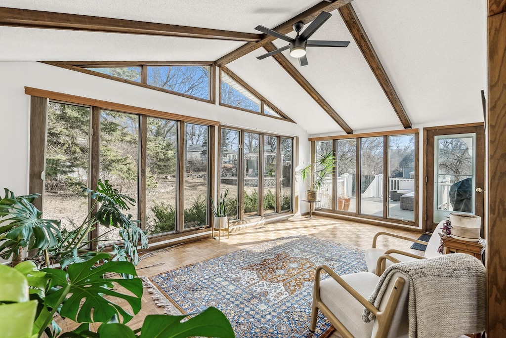 sunroom with lofted ceiling with beams and ceiling fan