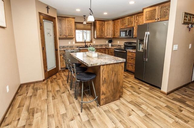 kitchen with pendant lighting, a breakfast bar, stainless steel appliances, light stone countertops, and a kitchen island