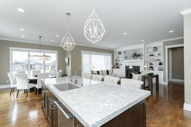 kitchen with an island with sink, ornamental molding, sink, and dark hardwood / wood-style flooring