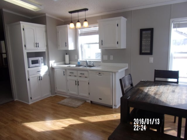 kitchen with sink, white appliances, decorative light fixtures, and white cabinets