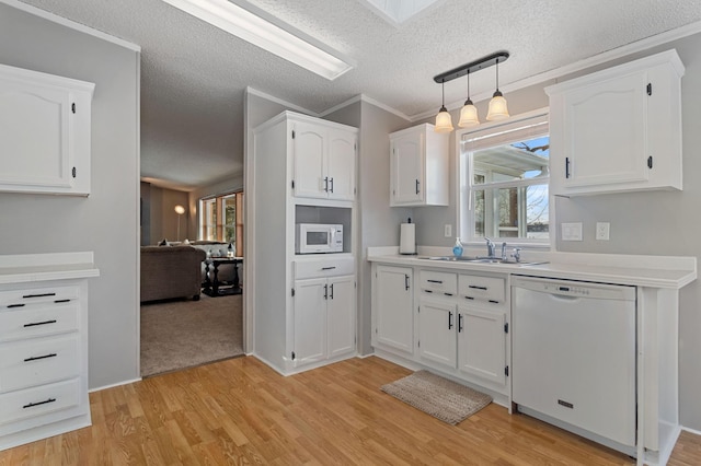 kitchen with sink, white cabinets, hanging light fixtures, light hardwood / wood-style floors, and white appliances