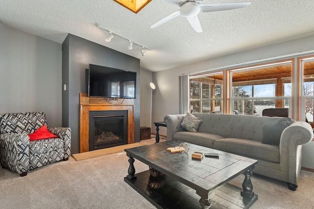 carpeted living room with ceiling fan, rail lighting, and a textured ceiling