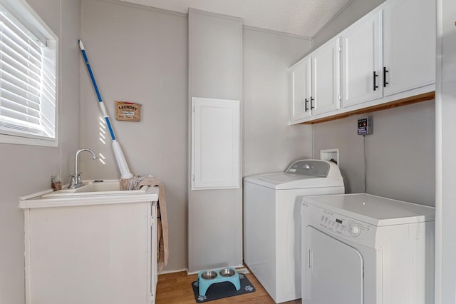 washroom with sink, light wood-type flooring, cabinets, independent washer and dryer, and a textured ceiling