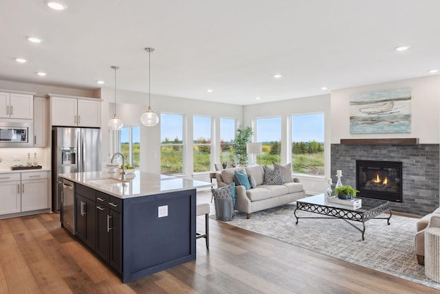 kitchen with pendant lighting, sink, white cabinetry, a kitchen island with sink, and stainless steel appliances