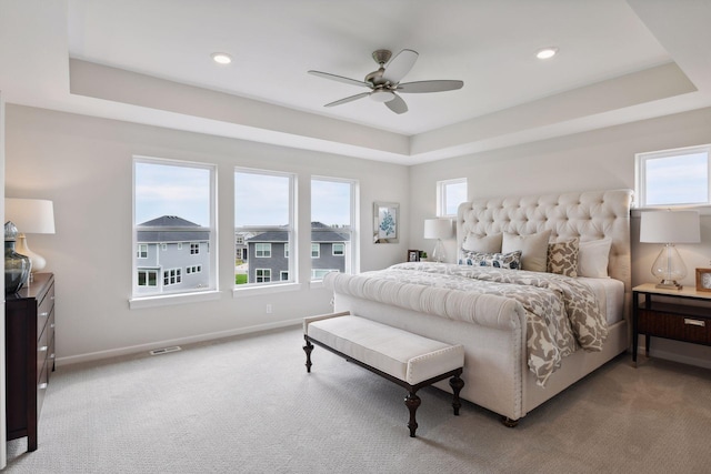 carpeted bedroom featuring a raised ceiling and multiple windows