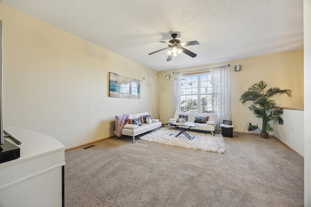 living area featuring ceiling fan, carpet, and a textured ceiling