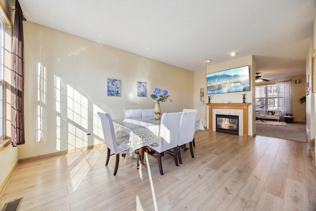 dining area with a textured ceiling, a fireplace, and light wood-type flooring