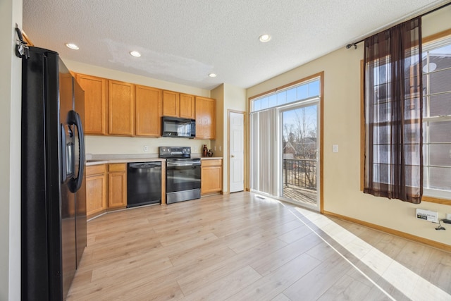 kitchen featuring light hardwood / wood-style flooring, black appliances, and a textured ceiling