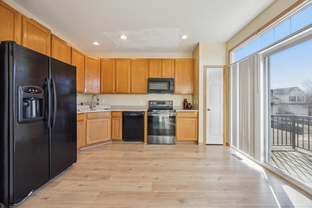 kitchen featuring sink, black appliances, a textured ceiling, and light wood-type flooring