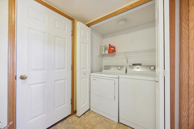 laundry area with separate washer and dryer, light tile patterned floors, and a textured ceiling