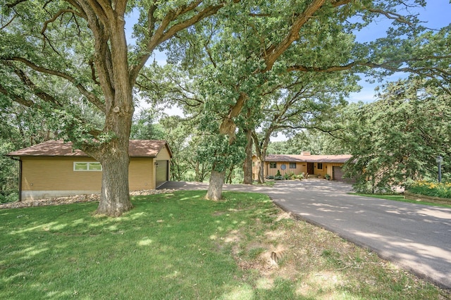 view of front of property featuring a front lawn, driveway, and roof with shingles