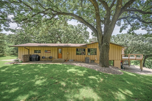 view of front of property featuring central AC unit, board and batten siding, a deck, and a front yard