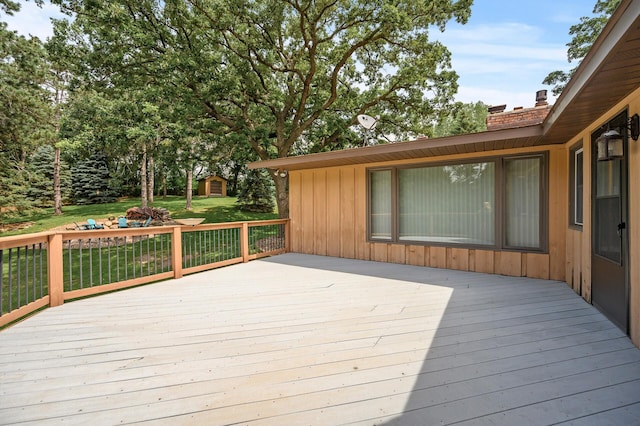 wooden terrace featuring a lawn, an outdoor structure, and a shed