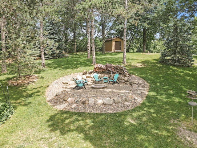 view of yard with a garage, a fire pit, an outbuilding, and a patio