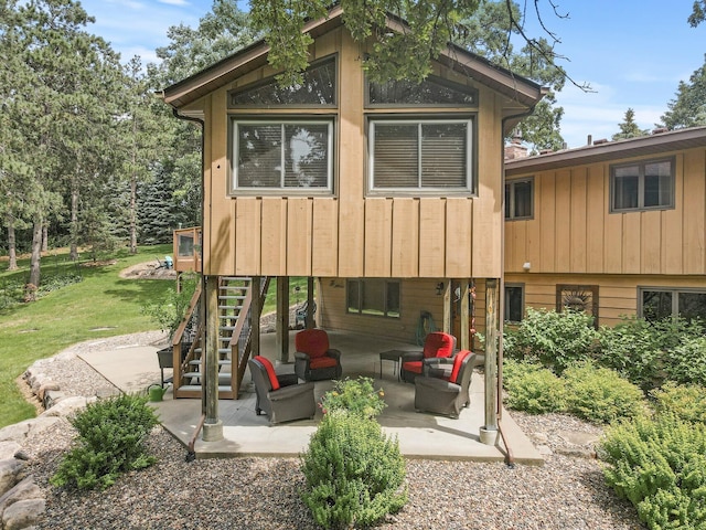 rear view of property featuring a patio area, stairway, an outdoor hangout area, and a yard