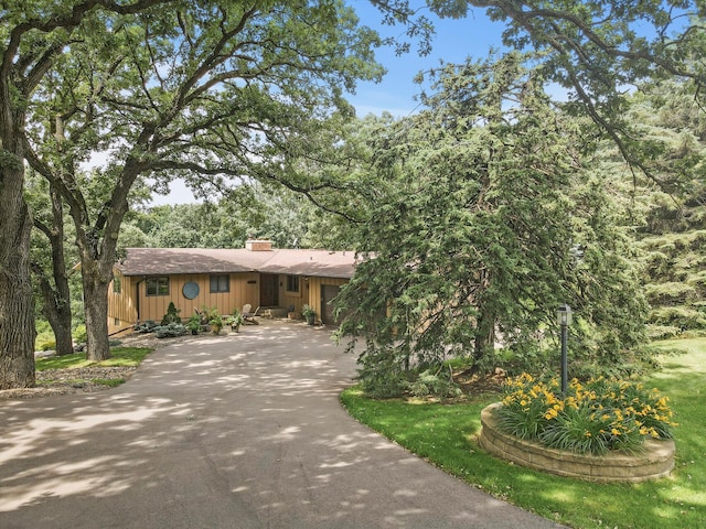 view of front of home with a chimney, driveway, board and batten siding, and an attached garage