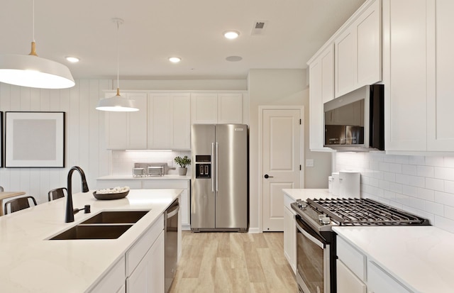 kitchen with pendant lighting, white cabinetry, stainless steel appliances, and sink