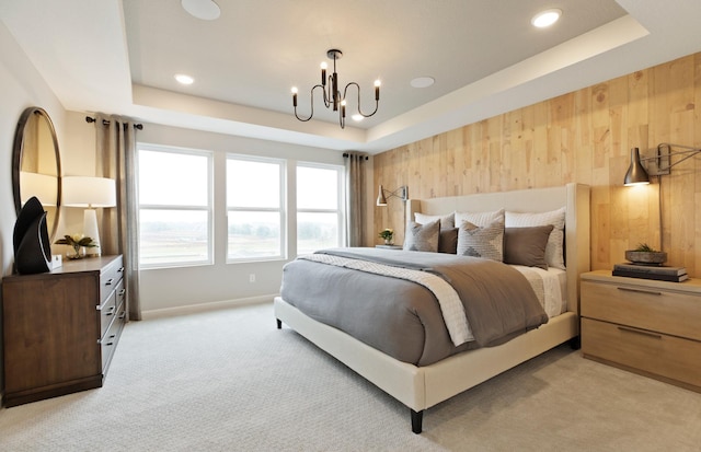 bedroom featuring wooden walls, a tray ceiling, a chandelier, and light carpet