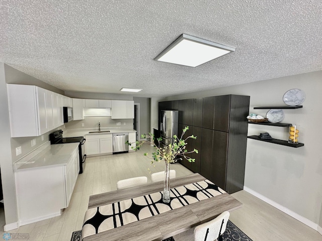 dining space with sink, light hardwood / wood-style flooring, and a textured ceiling