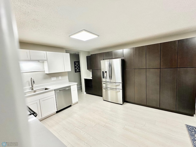 kitchen featuring stainless steel appliances, sink, light hardwood / wood-style flooring, and white cabinets