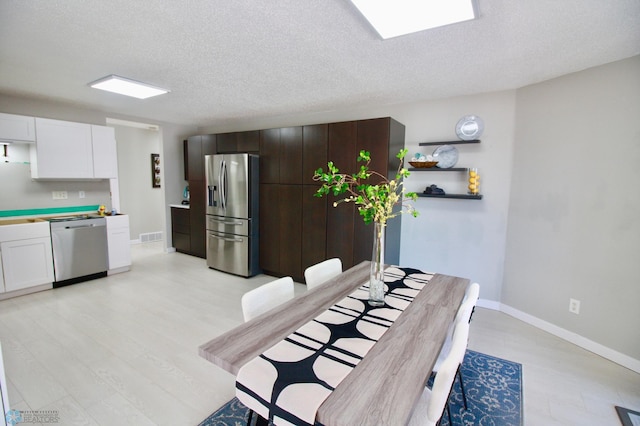 dining space featuring light hardwood / wood-style floors and a textured ceiling