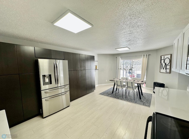 kitchen with stainless steel refrigerator with ice dispenser, light hardwood / wood-style flooring, and a textured ceiling